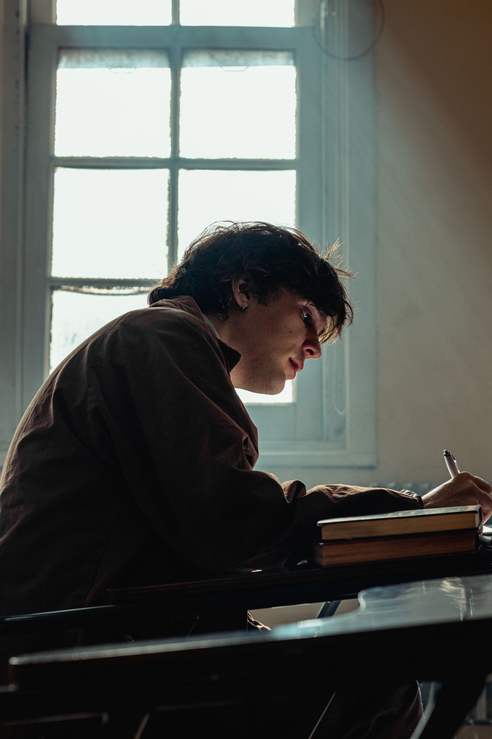 Student writing in a sunlit classroom